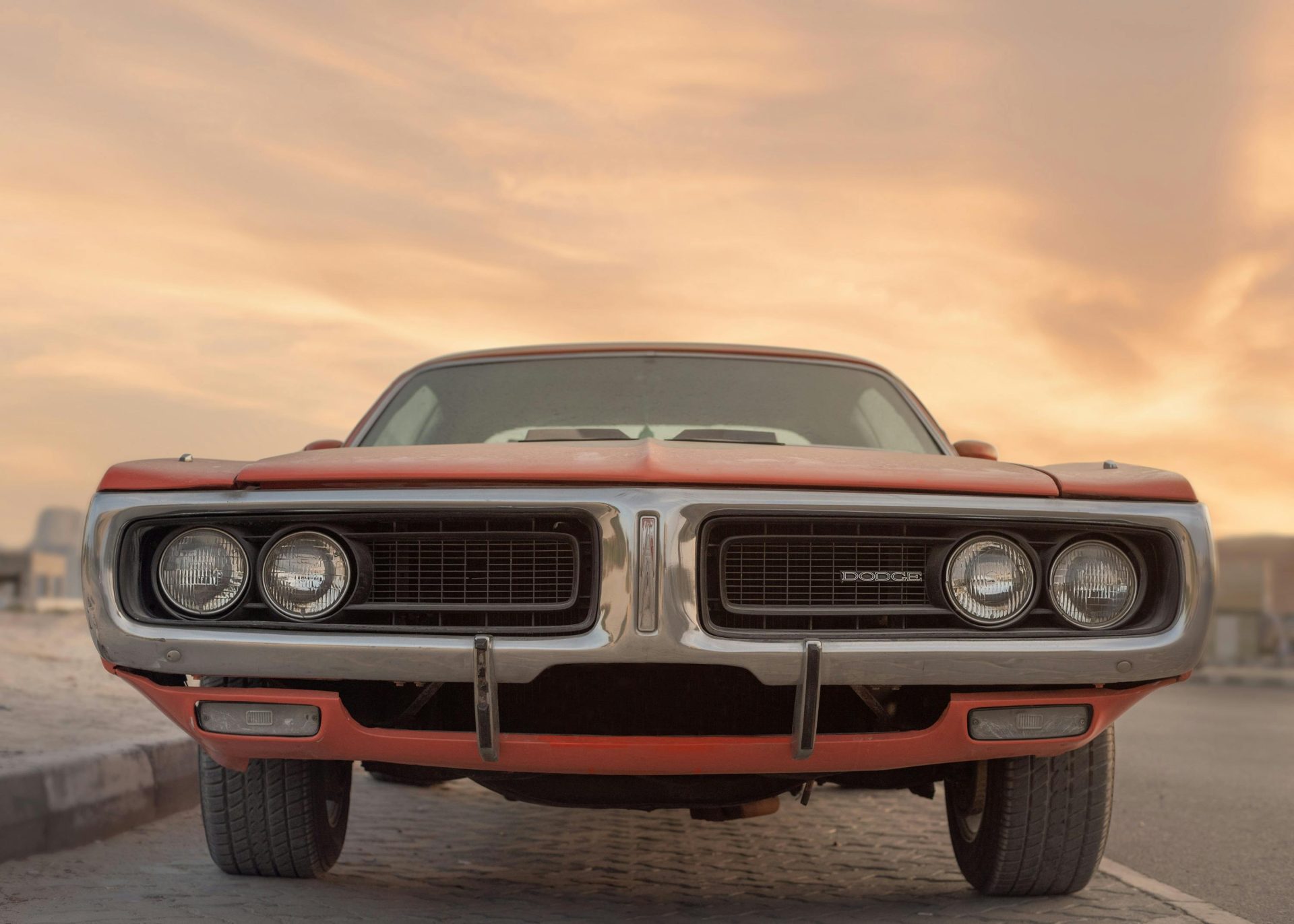 Vorderansicht eines klassischen Dodge Muscle-Cars unter einem leuchtenden Sonnenuntergang in Sharjah, VAE.